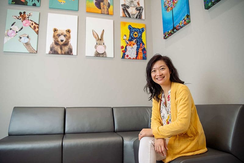 Jennie Chung Doctor Jennie Chung, sitting in on a couch in Happy Buns Pediatrics, Mckinney, Texas